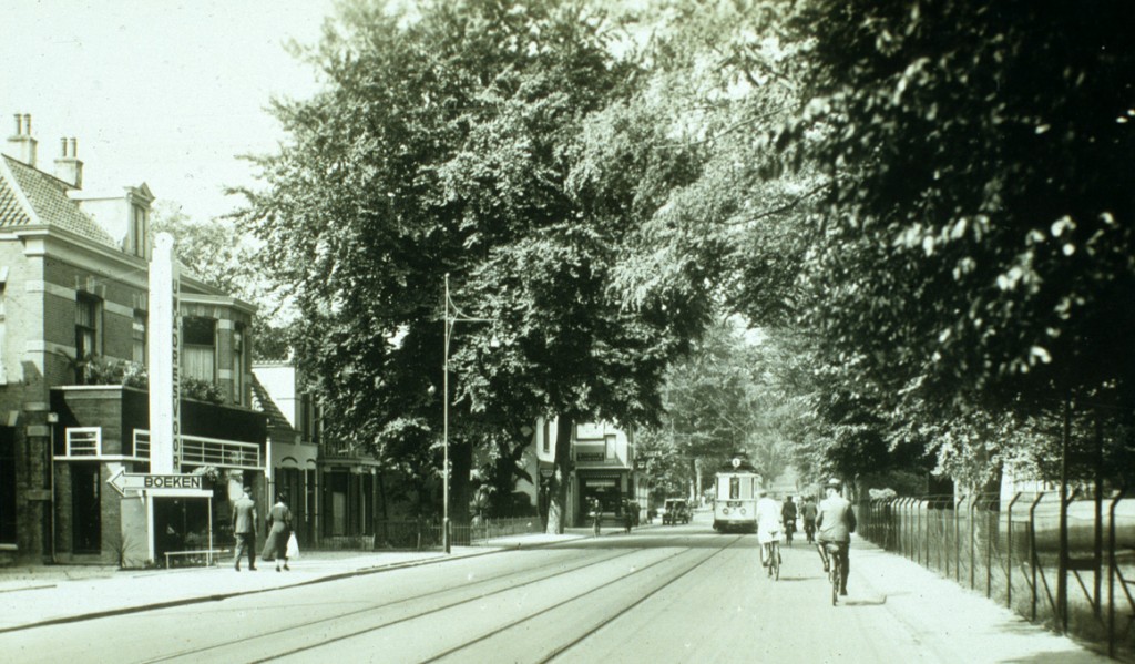 Links een pakkende reclamezuil voor de boekhandel Romijn. Rechts daarvan de villa Schoonoord waarin nu sinds 2011 de juwelier/antiquair Helldorfer een winkel heeft.