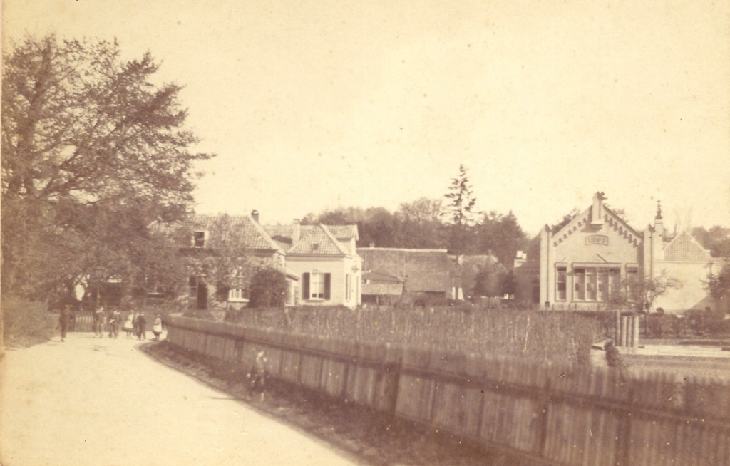 Een foto van rond 1890 met links, onder de boom, de ingang van de "Nattesteeg", de huidige "Rozensteeg". Het pad liep voor de Concertzaal langs over de "Eng" naar de Kneppelhoutweg. Het stuk over de "Eng" en daarna heet nu "Rozenpad". Rechts van her oorspronkelijke gebouw (onder het zadeldak) de oostelijk aangebouwde lokalen en rechts daar weer van de dienstwoning van de hoofdonderwijzer Aart van Ewijk.