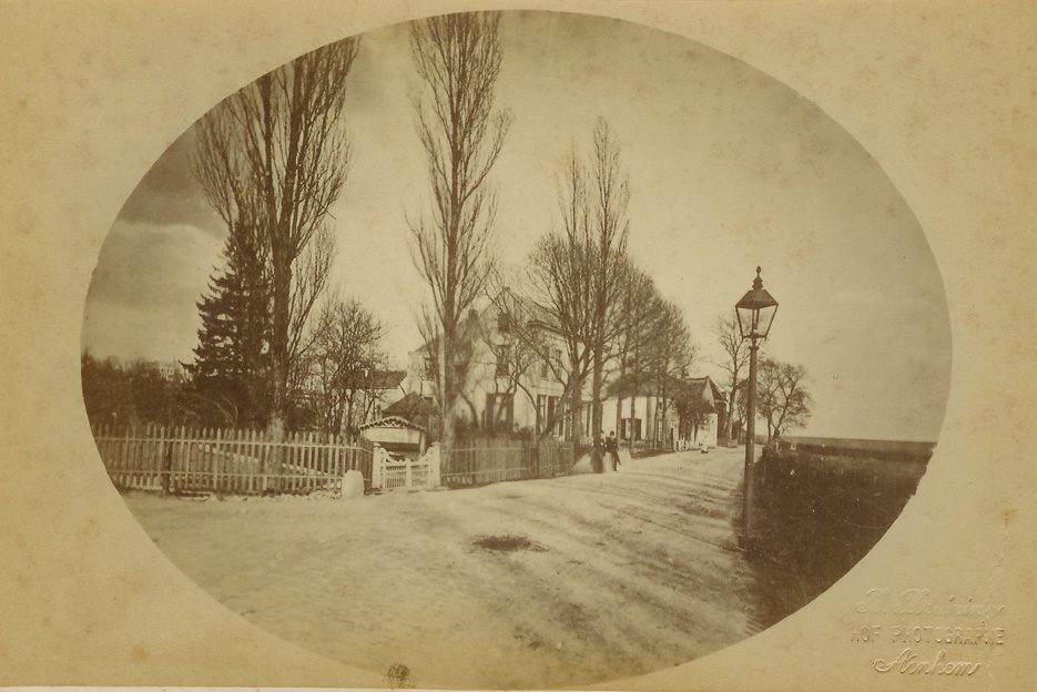 Op deze foto van rond 1900 is de rij panden tot aan het kruispunt Weverstraat/ Benedendorpsweg goed zichtbaar. Links van de lantaarnpaal, geheel achteraan, het kerkgebouw "Bethanië", daarvoor het kosterhuis van de Oude Kerk met in het achterhuis sinds 1820 de dorpsschool die in 1864 aan de Weverstraat werd ondergebracht (de OLS I)