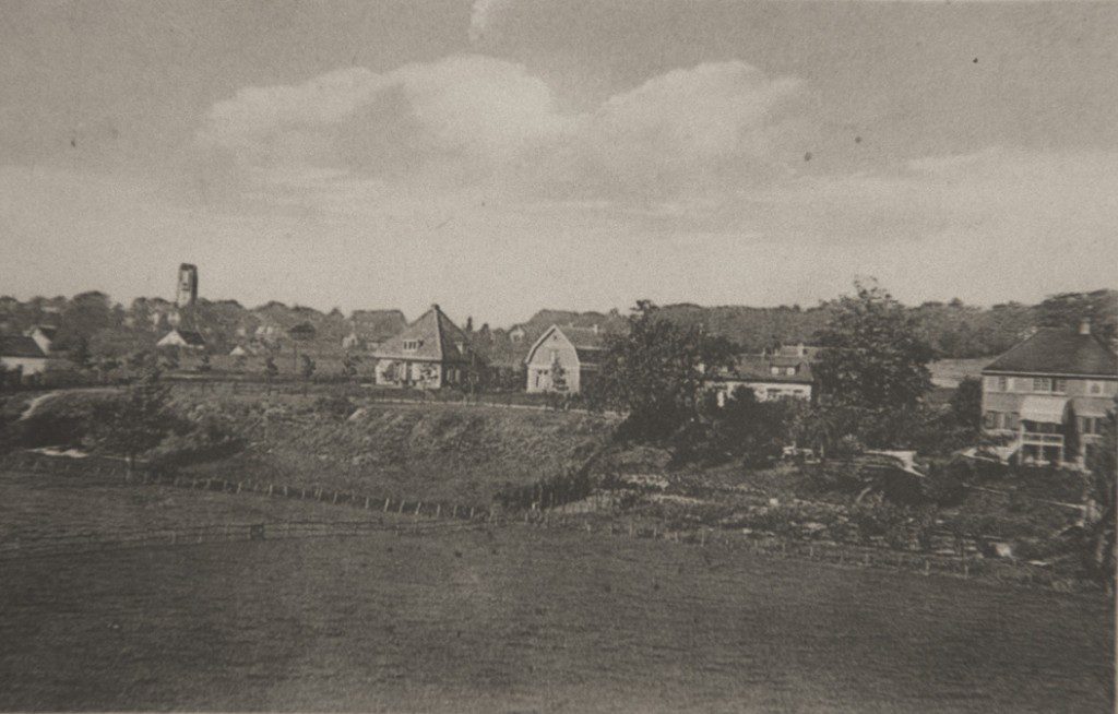 Zicht vanaf de spoordijk op de Benedendorpsweg. Geheel links het huis op nummer 4, gebouwd in 1916 met links daarvan "Ora et Labora". De twee meest links gelegen panden staan nu op nummer 9 en 11. Het rietgedekte huis links daar weer van, op de oosthoek van de Rosandeweg, is nog niet aanwezig. Het werd gebouwd in 1930.