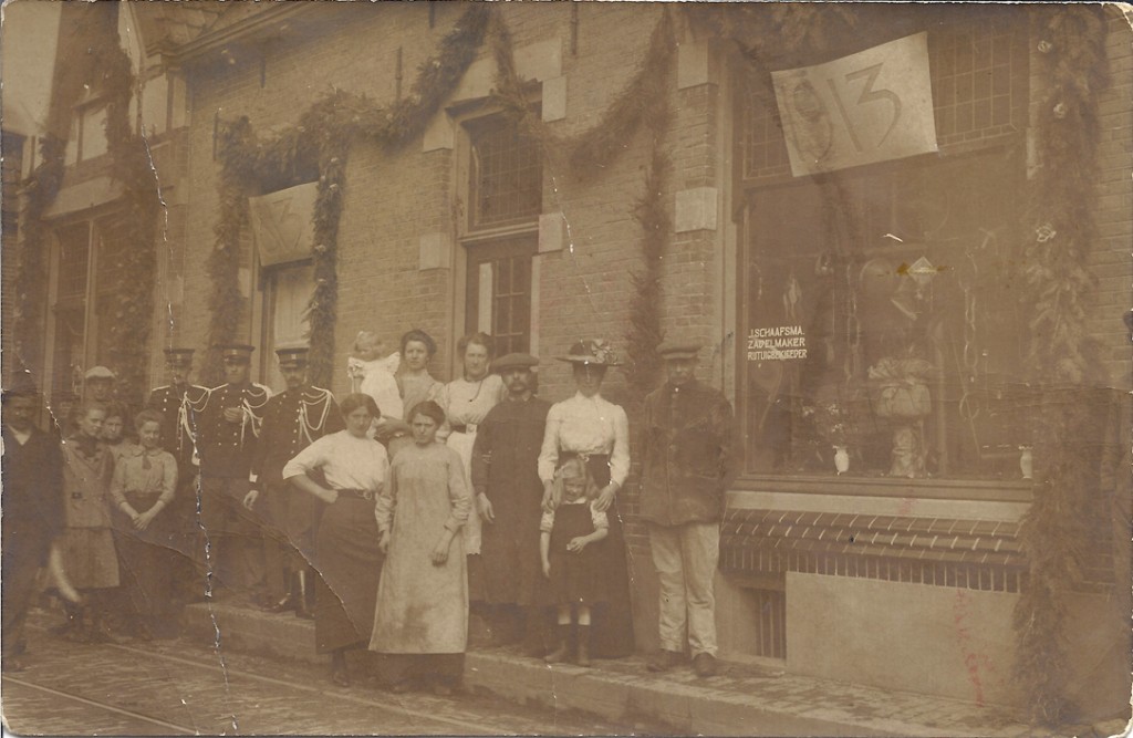 De winkel van J. Schaafsma in 1913. De zadelmaker/ rijtuigbekleder (met platte pet) staat derde van rechts. Links de kruidenierswinkel van zijn echtgenote.
