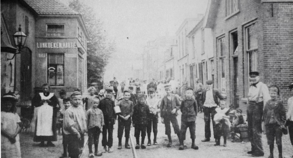 De situatie op de vorige afbeelding rechtsonder wordt hier weergegeven. Links de staldeuren van de oude achttiende-eeuwse herberg waarin in deze tijd, voor 1900, een kruidenierswinkel was gevestigd. Geheel links de derde waterpomp met lantaarn. Rechts herberg “De Rijnvaart” van de kastelein/scheepsbevrachter W.A. Potman, (Bij Beekhuizen Panman genoemd). In later jaren de stalhouderij Jan van Ee.