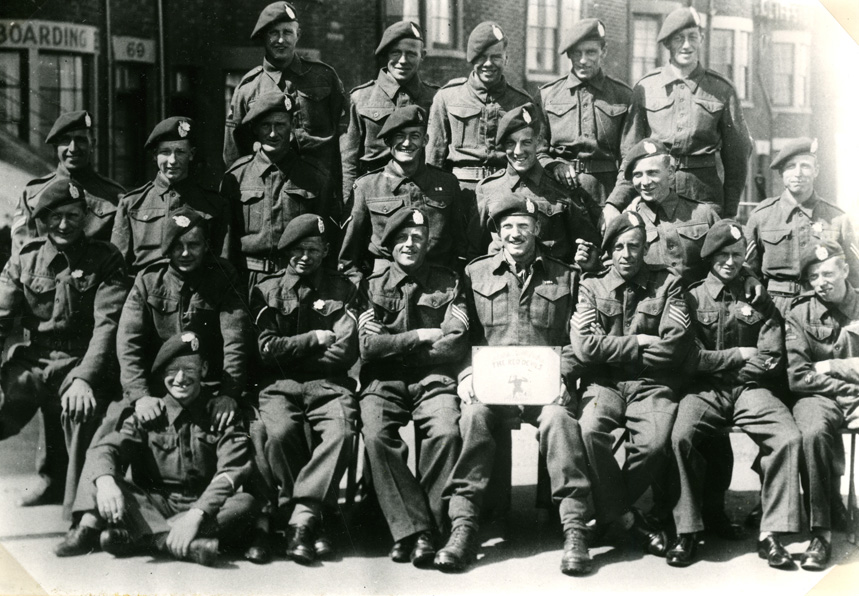 Mannen van No 15 Platoon, D Company, 7th Battalion, The King's Own Scottish Borderers, poseren voor de fotograaf in Scarbourough, Engeland. Op de voorgrond, de man met het bord, de commandant: Lt. Kipping. Links naast hem Sgt George Nattras. Bovenste rij, derde van links, Pt. Ure; hij sneuvelde in "the White House", Hotel Dreijeroord, te Oosterbeek
